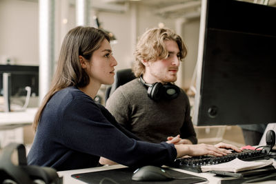 Side view of female entrepreneur working with coworker in office