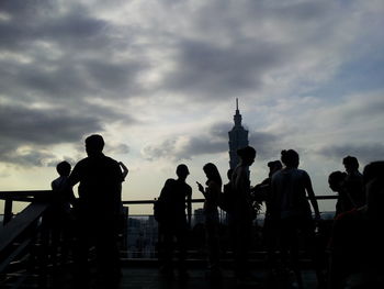 People at observation point by taipei 101 against sky during sunset