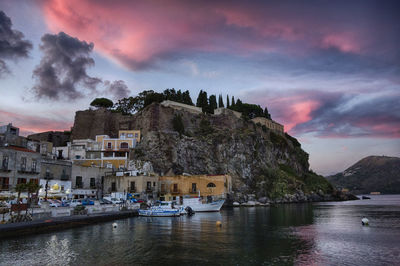 Low angle view of cliffed coastal town against pink sky