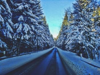 Road amidst snow covered trees against clear sky