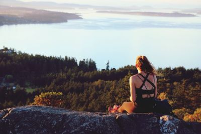 Rear view of woman sitting on landscape against mountain