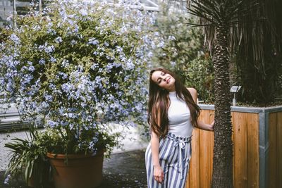 Young woman standing by flower tree