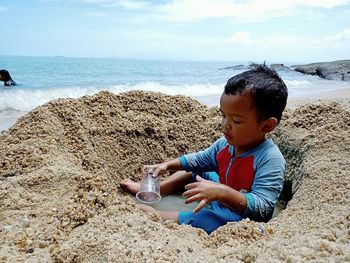 Rear view of boy digging his own pool by the beach