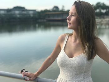 Young woman standing against lake