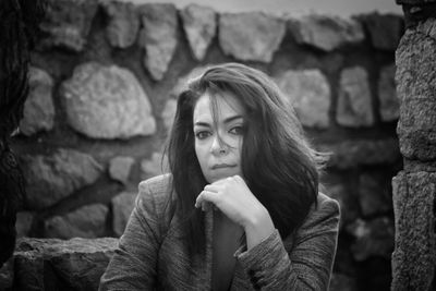 Portrait of woman sitting by stone wall