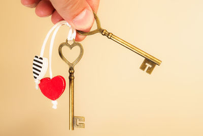 Close-up of hand holding key against white background