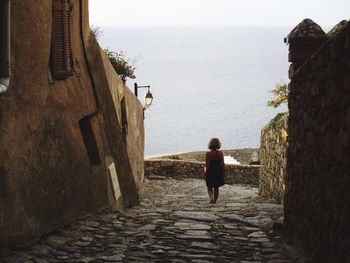 Rear view of woman walking in an old town by the sea
