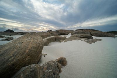 Rocks on shore against sky during sunset