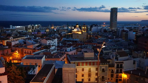 High angle view of illuminated city by sea