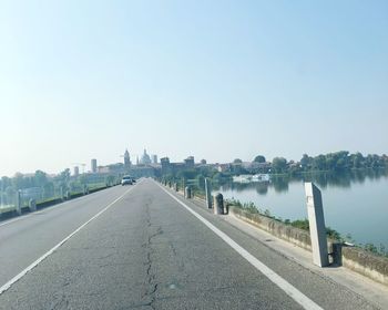 Road by river against clear sky