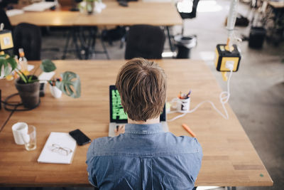 Rear view of computer programmer working at desk in creative office