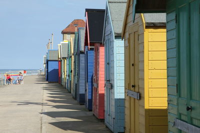 Beach huts on promenade against clear sky