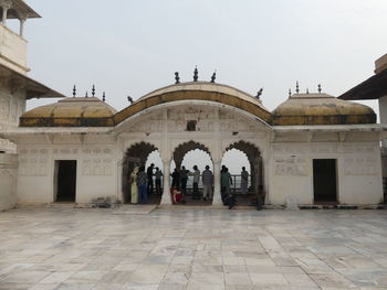 People in front of historic building against sky