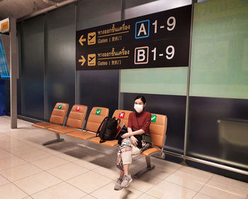 Full length of an asian woman waiting for the take off at an airport boarding gate