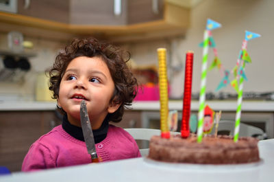 Thoughtful girl sitting by cake on table