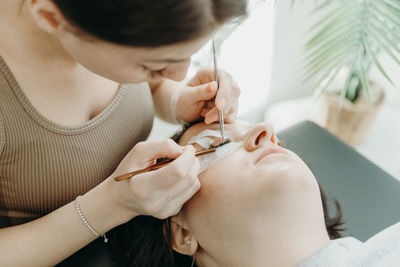 Portrait of a girl cosmetologist extending eyelashes to a woman.