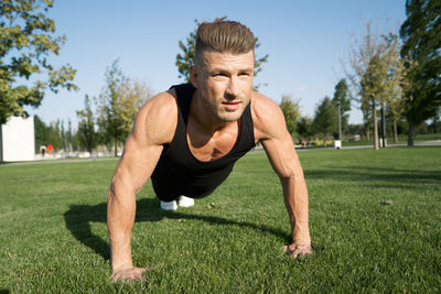 Portrait of young man exercising on field