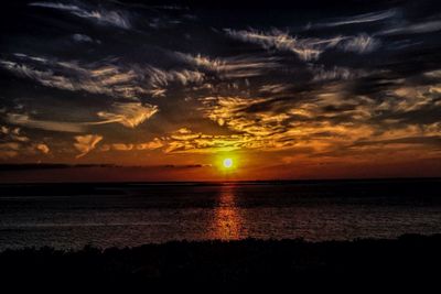Scenic view of sea against dramatic sky during sunset