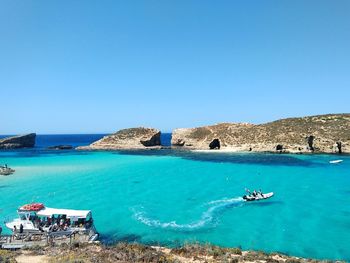 People riding boats in sea against clear sky