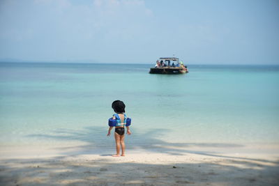 Rear view of child standing at beach