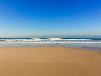 Scenic view of beach against clear blue sky