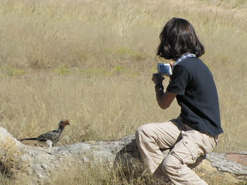 Woman photographing bird on field