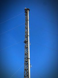 Low angle view of communications tower against clear blue sky