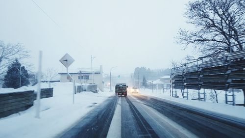 Cars on road in city against clear sky during winter