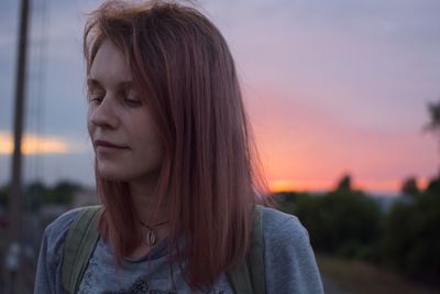 Portrait of woman looking away against sky during sunset