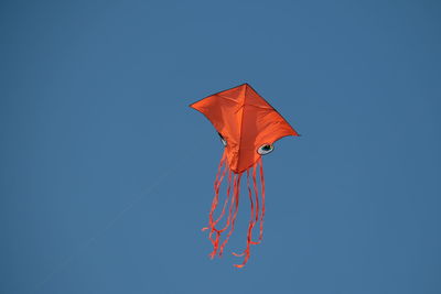 Low angle view of kites flying against clear blue sky