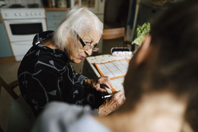 Senior woman talking with female healthcare worker in kitchen at home