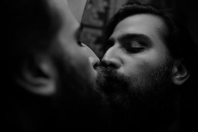 Close-up of bearded man kissing on mirror