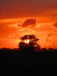 Silhouette trees on field against romantic sky at sunset