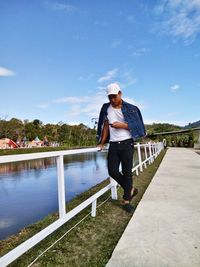 Full length of man standing by railing against sky