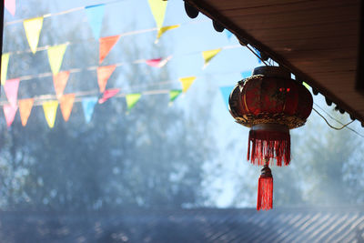 Low angle view of lanterns hanging from roof against sky