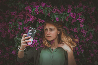 Beautiful woman taking selfie against plants