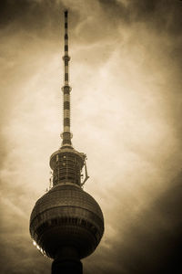 Low angle view of communications tower in city against sky