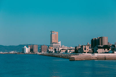 City at waterfront against blue sky