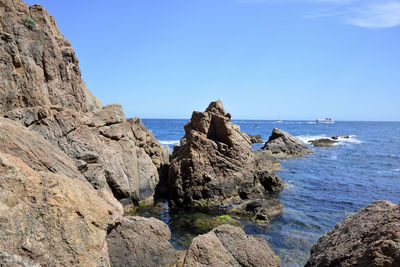 Panoramic view of rocks on beach against clear blue sky