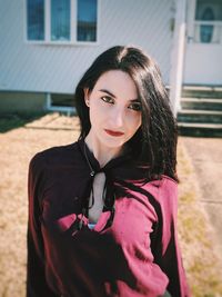 Portrait of young woman standing against building