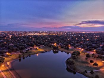 High angle view of illuminated city buildings against sky at sunset