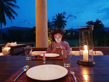 Woman using mobile phone while sitting on sofa at restaurant