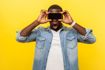 Full length portrait of man wearing mask against yellow background