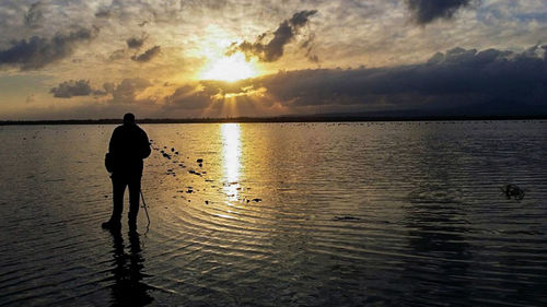 Scenic view of sea against cloudy sky at sunset