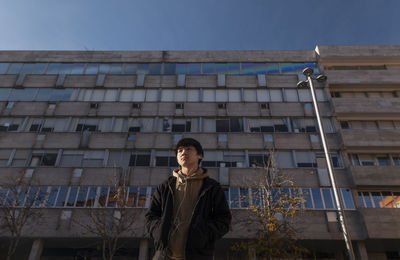 Asian teenage boy with earphones against building on street. madrid. spain