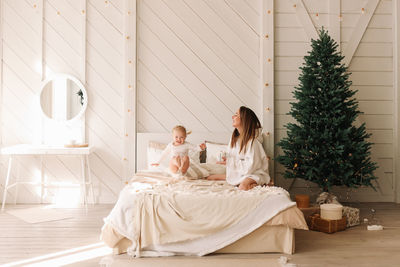 Woman sitting on bed by tree