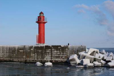 Lighthouse by sea against sky