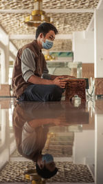 Side view of young man sitting on glass