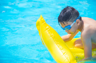 Rear view of shirtless boy swimming in pool
