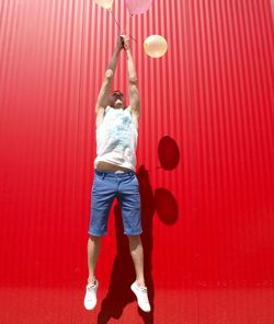 Full length of woman standing against red wall